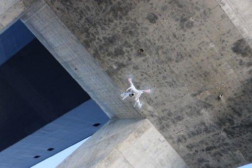 photograph of a drone flying beneath a concrete bridge